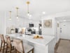 Your sleek white kitchen features a spacious island for meal prep, modern appliances, and warm pendant lighting for cooking together.