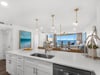 Your gourmet kitchen features pristine white countertops and modern appliances, perfectly framed by stunning ocean views through floortoceiling windows.
