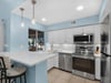 Your modern kitchen invites culinary adventures with gleaming stainless appliances, white quartz counters, and cheerful blue accents that brighten your cooking experience.