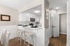The modern kitchen features crisp white cabinetry and a breakfast bar