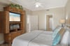 Relax in the peaceful bedroom with coastal charm, featuring a comfortable bed and entertainment center for cozy evenings in.
