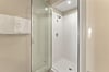 Step into the private glassenclosed shower with fresh white tiles and plush towels ready for your comfort.