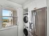 Your bright laundry nook features stacked washer and dryer with crisp white cabinetry