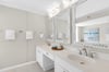 Pamper yourself in this pristine bathroom featuring dual vanities, weathered wood mirrors, and coastal touches that create your perfect morning routine.