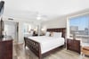 Sink into crisp linens and rich wood furnishings in bedroom 1, where city views and gentle ceiling fan breezes create the perfect retreat.