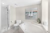 Unwind in your spalike bathroom with a soaking tub and separate glass shower, complete with coastal artwork for a serene retreat.