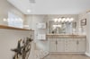 The coastalinspired bathroom features warm wood accents and soft light through frosted glass