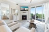 Step into your bright, coastalchic living room where plush seating and a cozy fireplace invite you to relax after sunsoaked days. Large windows frame your private balcony views of endless greenery.