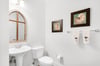 The powder room features coastal accents, soft lighting, and a charming arched mirror.