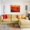 Sink into the plush sectional and let the vibrant sunset painting transport you to peaceful evenings. Warm throw pillows and coastal charm create your perfect relaxation spot.