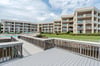 Threestory property features tiered architecture with multiple balconies, manicured lawn, swimming pool, and waterfront access via private boardwalks.
