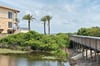 Waterfront property featuring palm trees, coastal views, and direct boardwalk access to nearby beaches and natural landscapes.