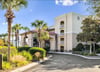 A welcoming property nestled among lush palm trees and manicured landscaping, featuring Mediterraneaninspired architecture with a covered entrance and multiple balconies overlooking beautifully maint