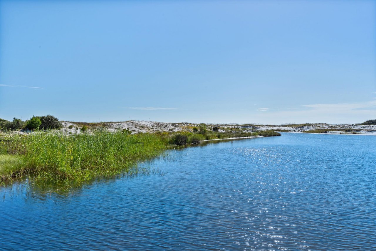 2191166 A Body Of Water With Grass And Trees Around It