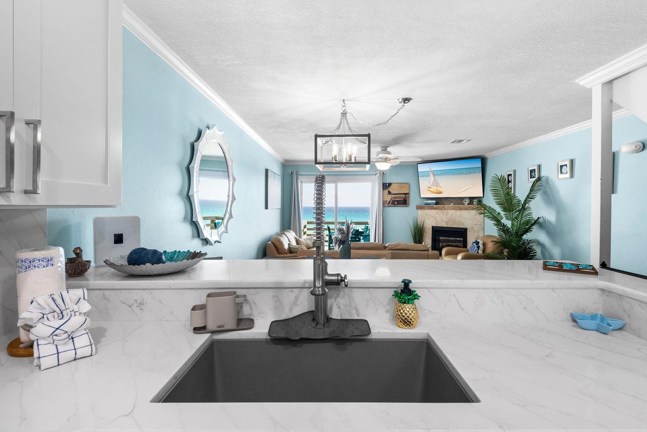 The kitchen flows seamlessly into the living area, where ocean views and coastal charm create the perfect backdrop.