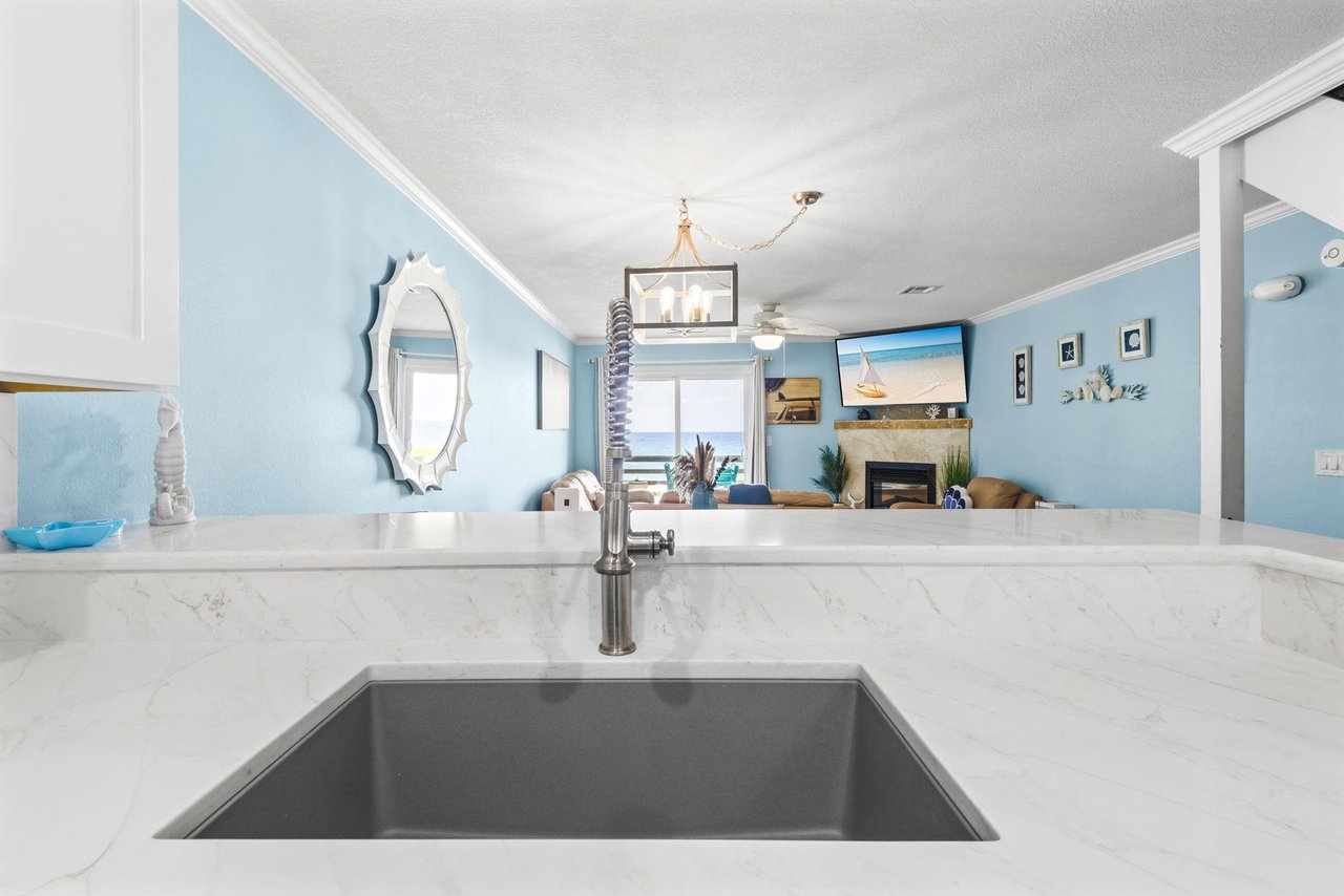 The kitchen flows seamlessly into the living area, where ocean views and coastal charm create the perfect backdrop.