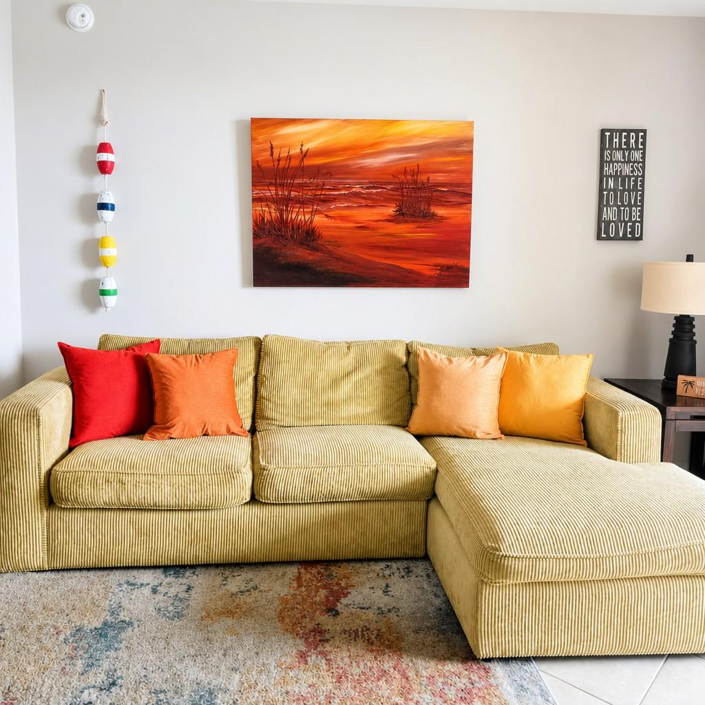 Sink into the plush sectional and let the vibrant sunset painting transport you to peaceful evenings. Warm throw pillows and coastal charm create your perfect relaxation spot.