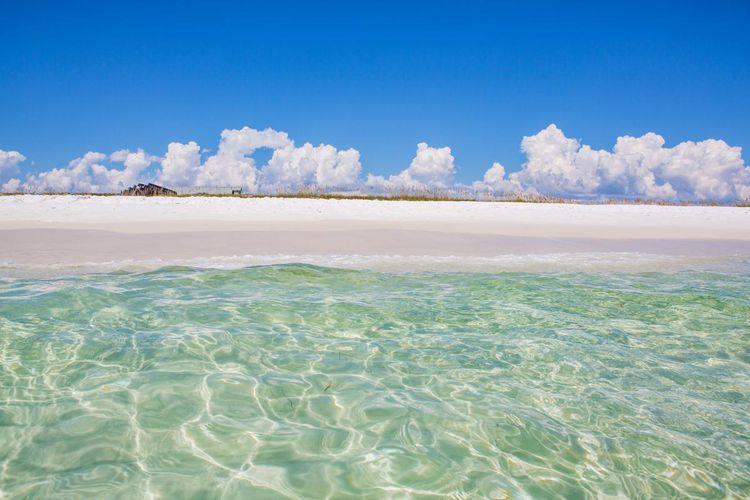 2268017 A Body Of Water With A Beach And Clouds In The Background