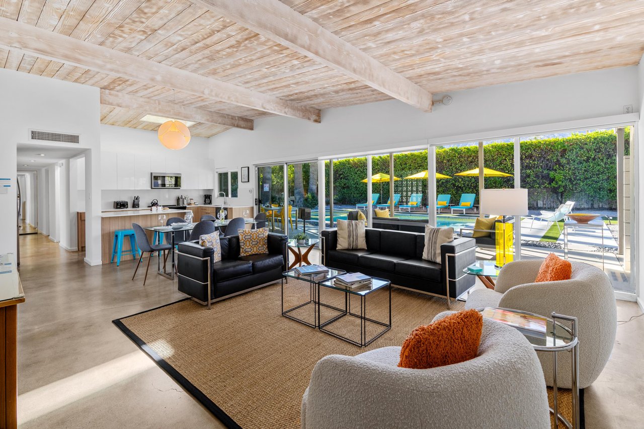Relax in this stunning openplan living space where exposed beams meet modern comfort, with seamless pool access through floortoceiling windows.