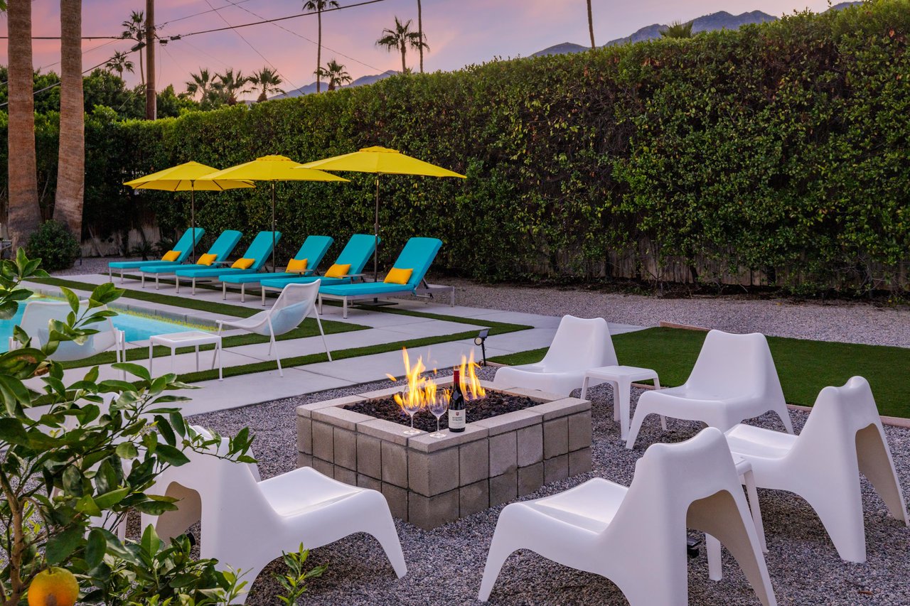 Outdoor fire pit area with modern seating surrounded by lush landscaping and mountain views at dusk.