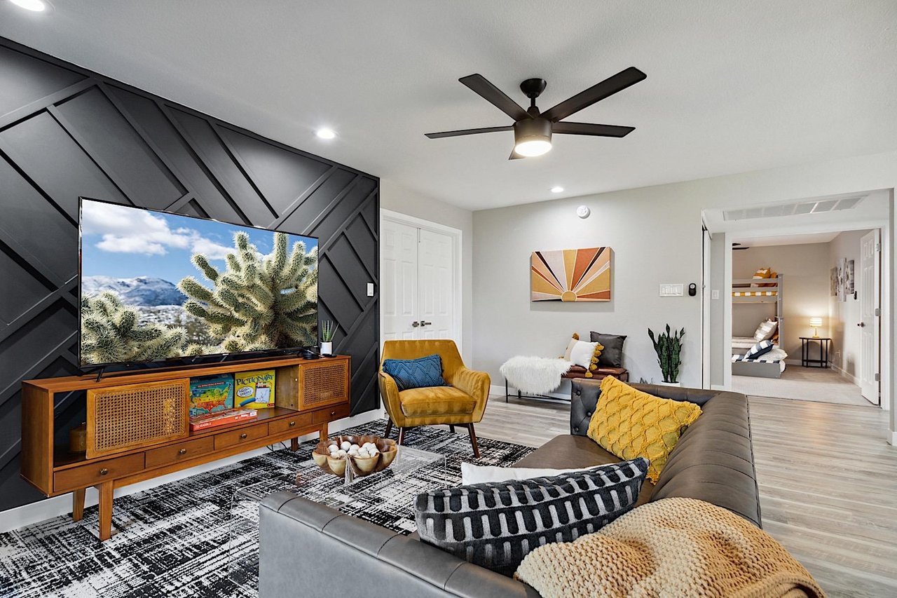 Living Room. Faux leather sofa, mustard sitting chair, clear coffee table, 65 Smart TV w Streaming