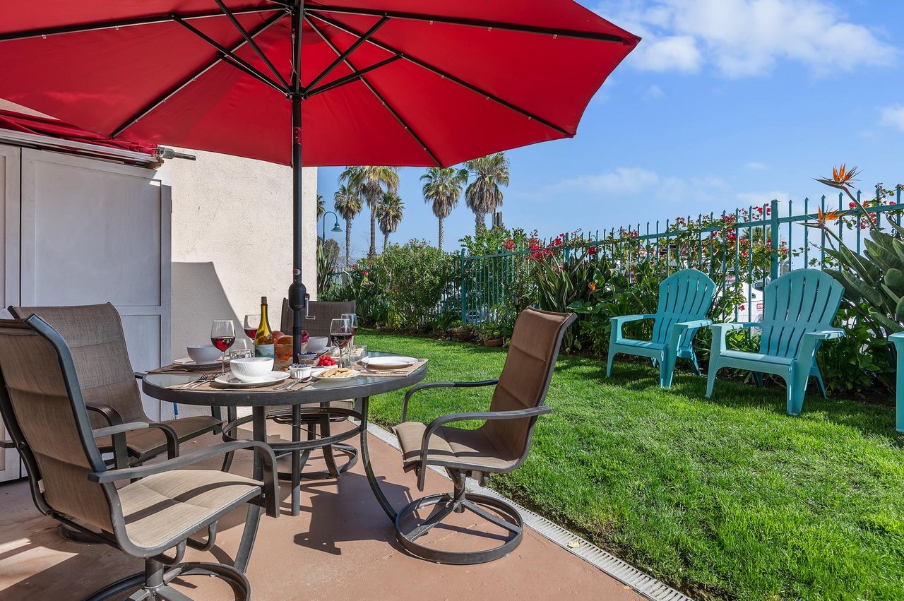Furnished patio with table, chairs and umbrella. You can take the chairs onto the grass and enjoy the breeze off the beach.