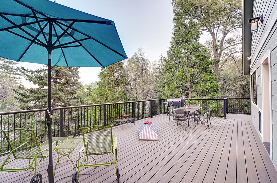 Spacious deck with mountain and forest views, outdoor games, BBQ, and deck seating.