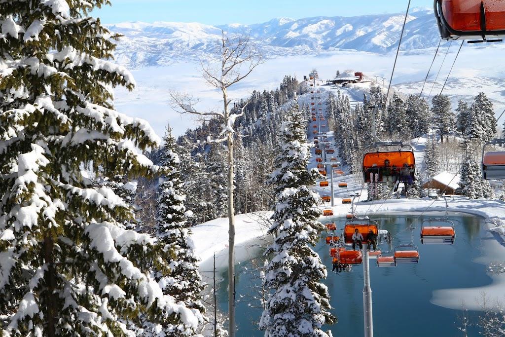 The Canyons ski area orange bubble lift traveling over a snowy mountain with icy lake below.