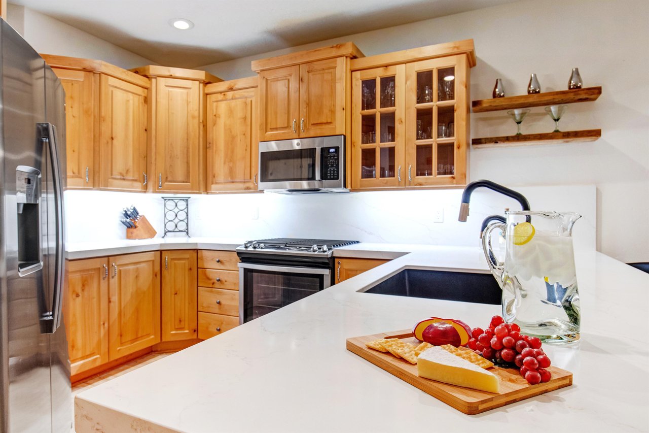 This Park City Lodging vacation rental offers a fullyequipped kitchen with white countertops and warm wood cabinetry.