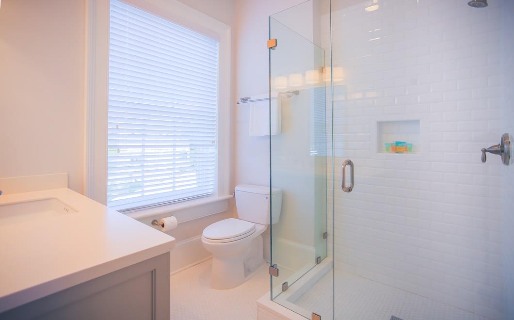 The upstairs bathroom has a glass enclosed shower and rainfall shower head.