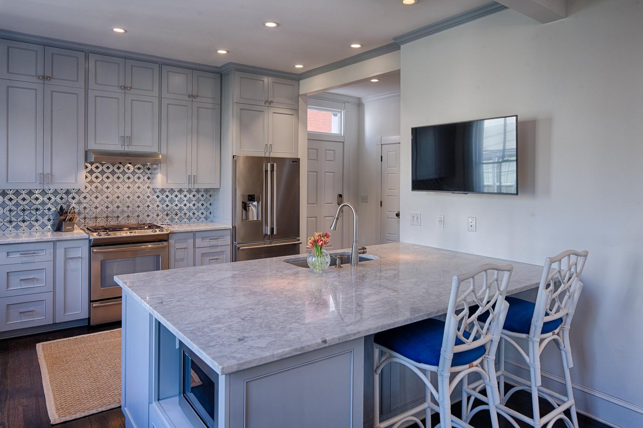 A smart television is mounted in the kitchen on a swivel mount for guest enjoyment.