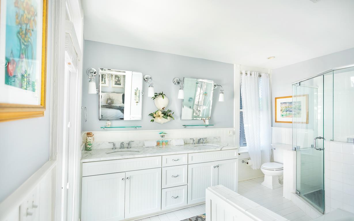 This bathroom has a double vanity, with marble countertops and a private balcony.