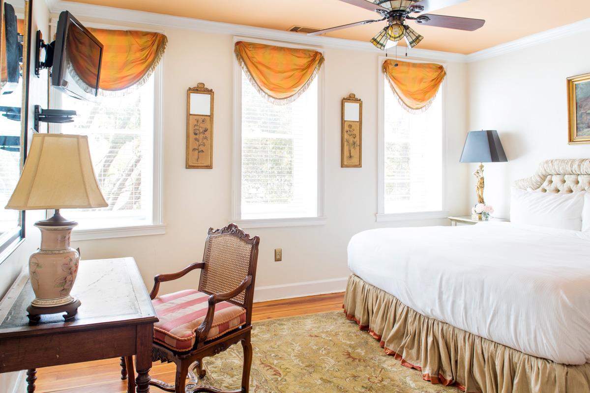 The primary bedroom features Southern decor and an antique writing desk.