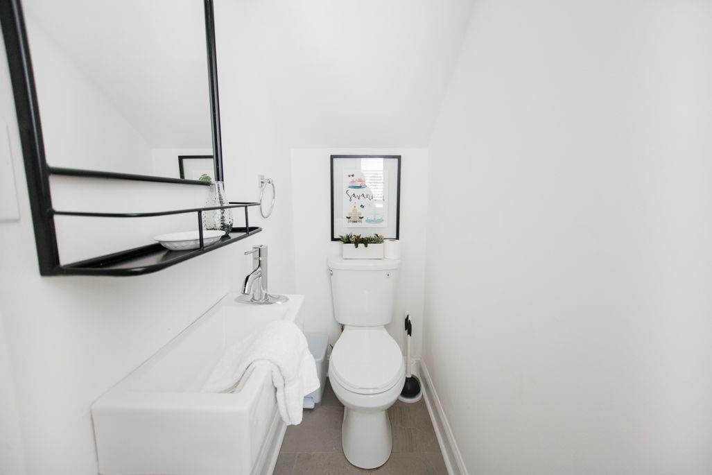 Just between the living room, and the kitchen, a half bath has been tucked beneath the staircase.