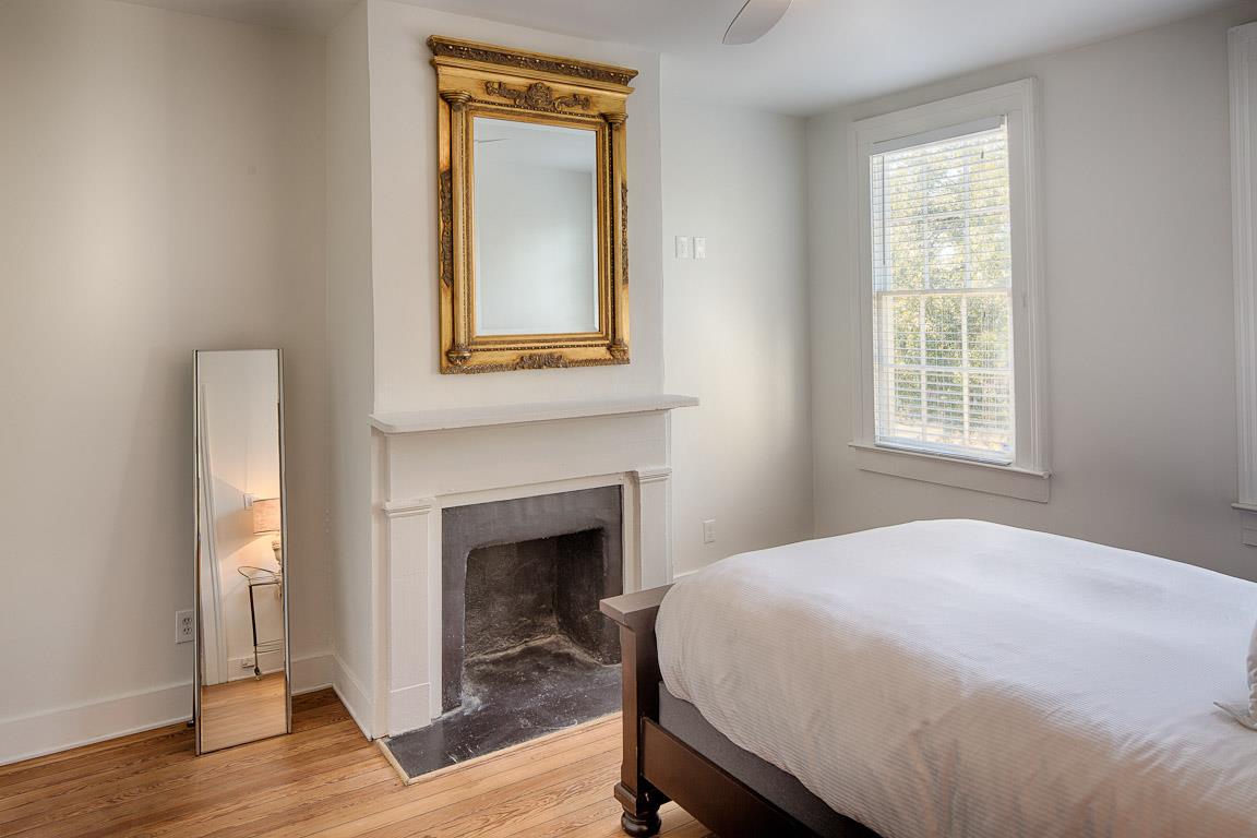 A tall mirror leanings next to the fireplace for getting ready.