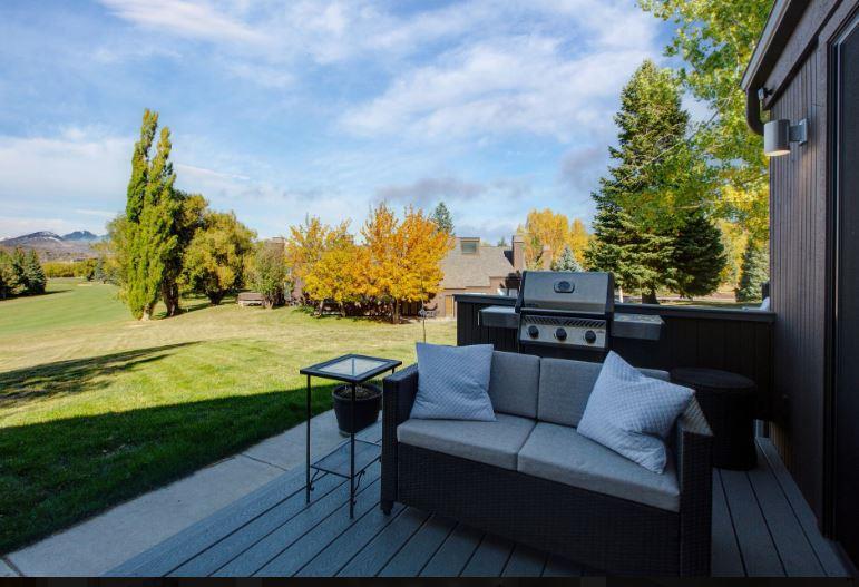 Expansive private deck with BBQ grill and stylish outdoor furnishings, offering breathtaking panoramic views of the golf course and resort area.