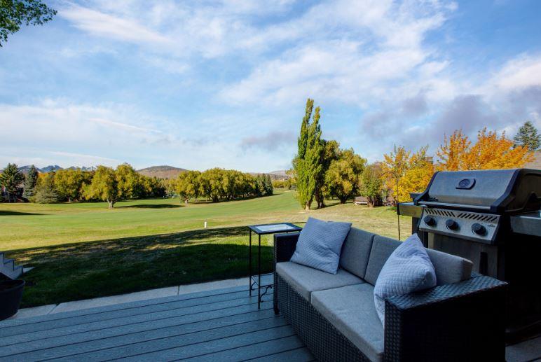 Expansive private deck with BBQ grill and stylish outdoor furnishings, offering breathtaking panoramic views of the golf course and resort area.