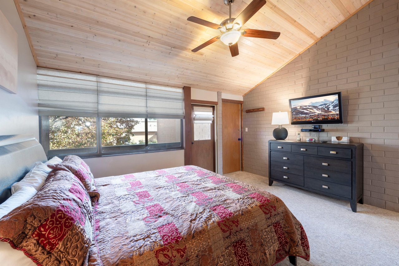 The king master bedroom at Park Avenue 235 offers a vaulted wood ceiling, ceiling fan, and inroom TV — the perfect space to unwind after a day on the mountain.