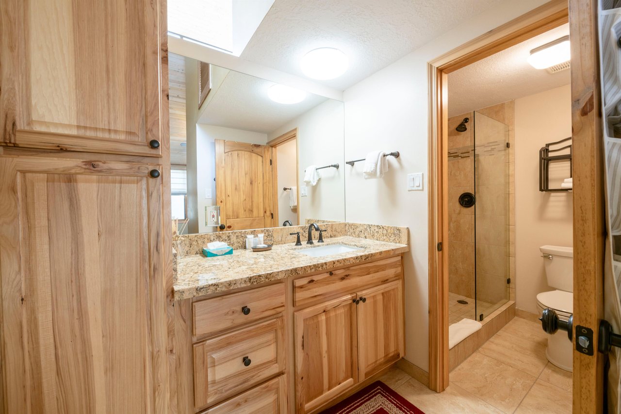 A beautifully updated bathroom at Park Avenue 235 features a granite vanity, custom cabinetry, and a tiled walkin shower for a touch of spalike comfort.