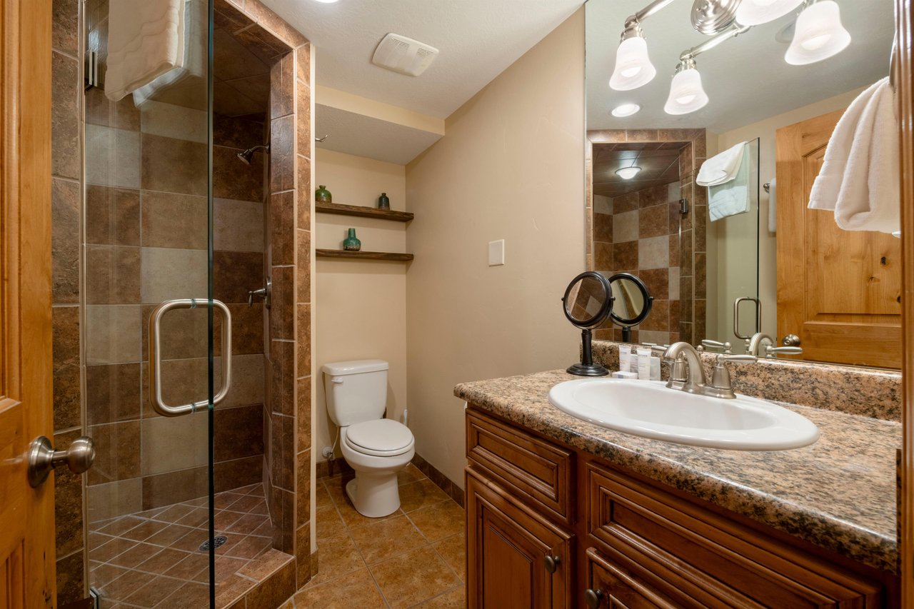 The beautifully appointed bathroom at Park Avenue 211 features a spacious walkin shower no tub, granite vanity, and warm, tasteful finishes throughout.
