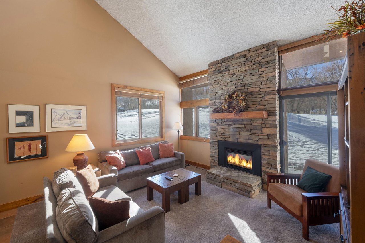 Cozy up by the stone gas fireplace in the living room at Park Avenue 224 — the perfect spot to unwind after a day on the slopes.