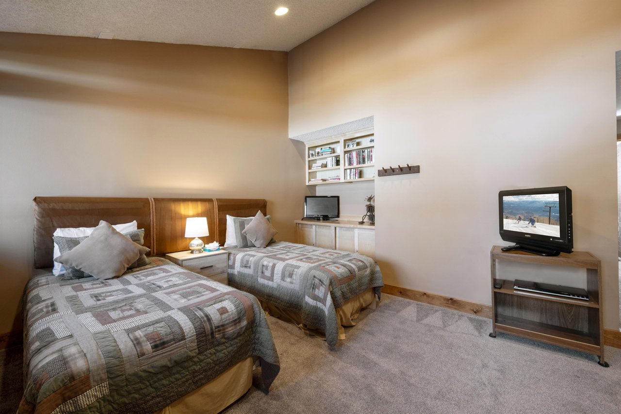 The twin bedroom at Park Avenue 224 comfortably sleeps two with builtin shelving and its own TV — a great setup for kids or extra guests at this Park City vacation rental.