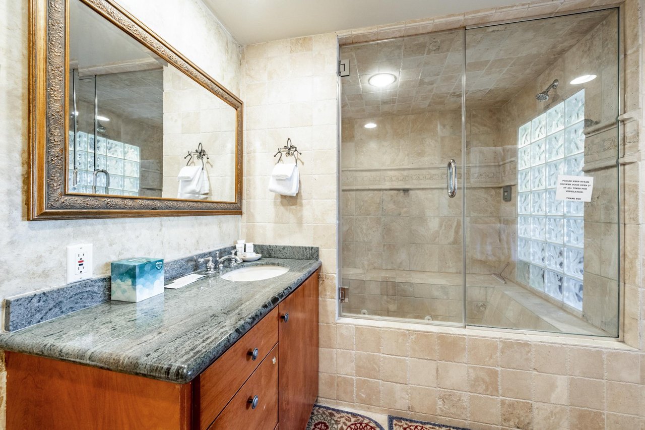 Freshen up in style in the spainspired bathroom at Park Avenue 245, where stone tile, granite countertops, and a glass walkin shower make every morning feel like a luxury Park City condo rental expe