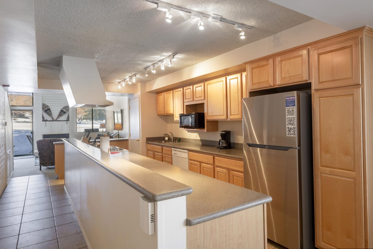 The wellequipped kitchen at Park Avenue 251 features generous counter space, light wood cabinetry, and modern stainless steel appliances — everything needed for a fully selfsufficient Park City cond