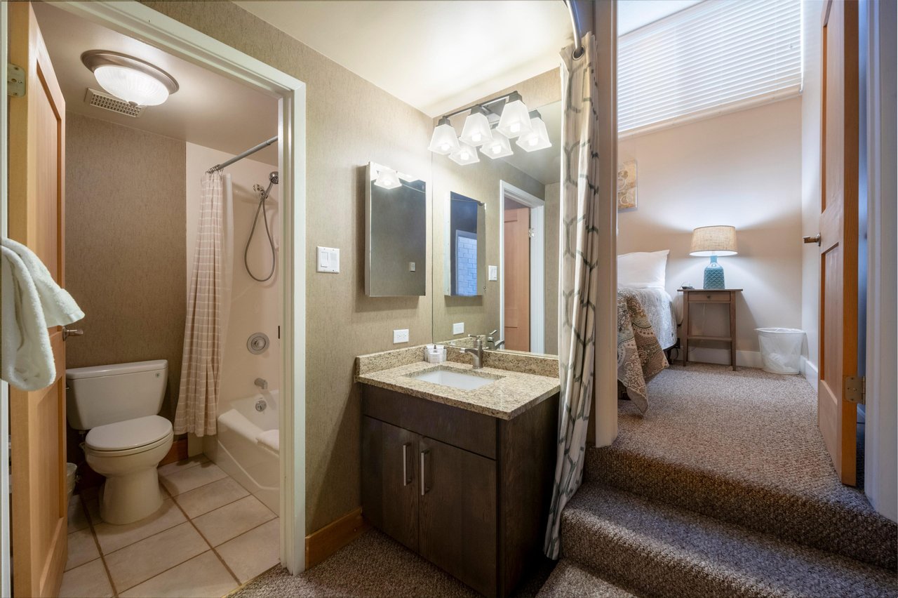 The shared bathroom at Park Avenue 256 features a warm wood vanity, granite countertop, and combination tub and shower — a wellappointed and accessible space that adds everyday comfort to this sought