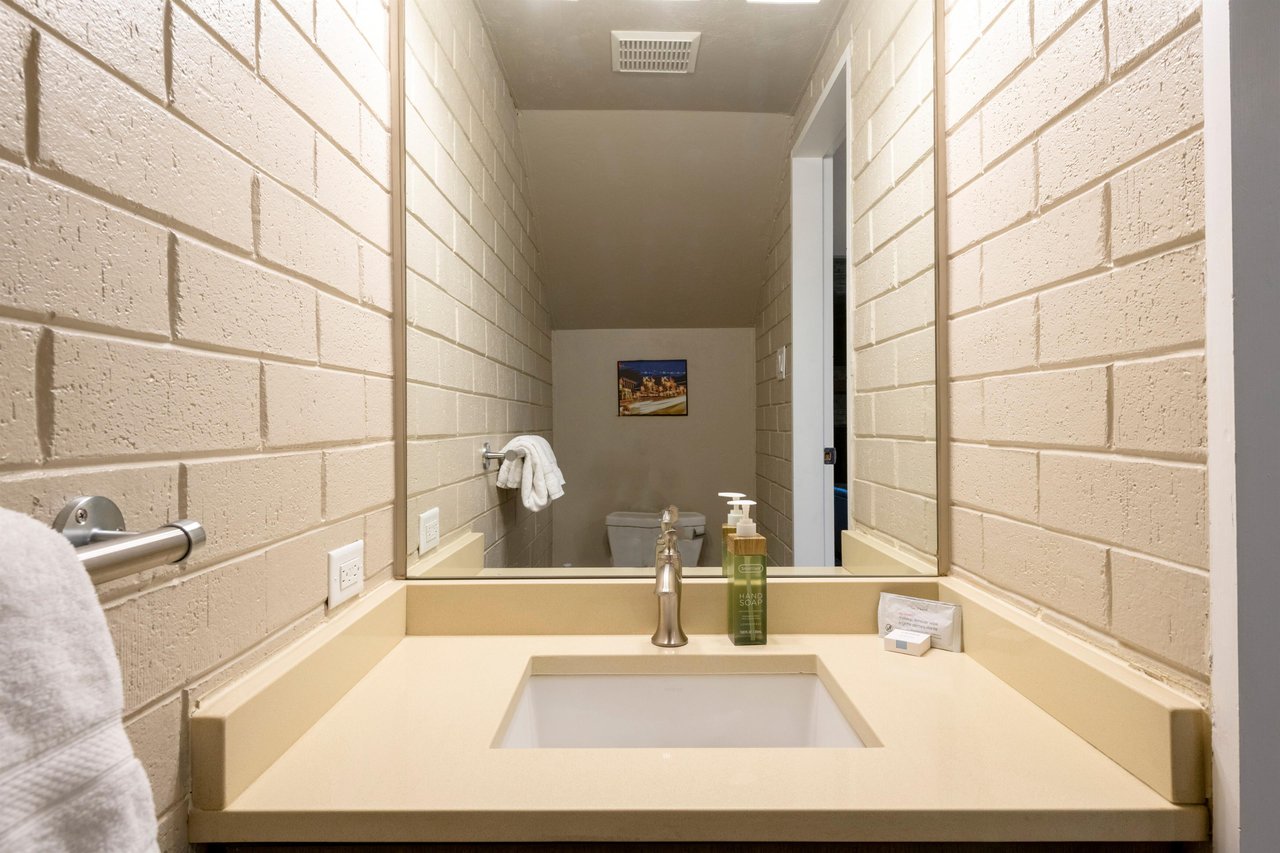 The sleek and stylish main level half bathroom at Park Avenue 256 features a cleanlined vanity, warm tile walls, and modern finishes — a thoughtful and convenient touch that enhances this premier Par