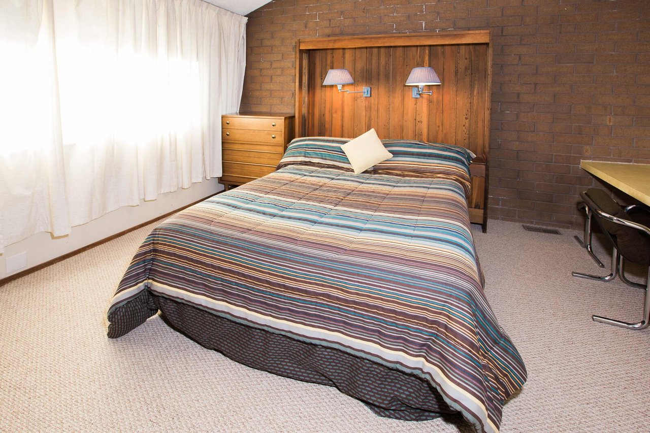 Rest up for another day of adventure in the cozy queen bedroom at Park Avenue 314. Warm wood accents, exposed brick, and colorful bedding give this room a charming, mountain lodge feel that guests lov