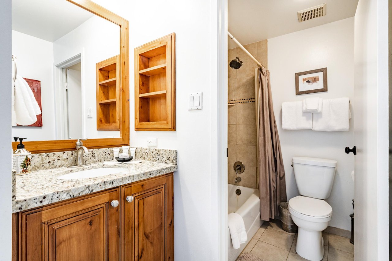 The shared bathroom at Park Avenue 333 is wellappointed with warm wood cabinetry, granite countertops, and a tubshower combo — everything guests need for a comfortable and convenient stay at this Pa
