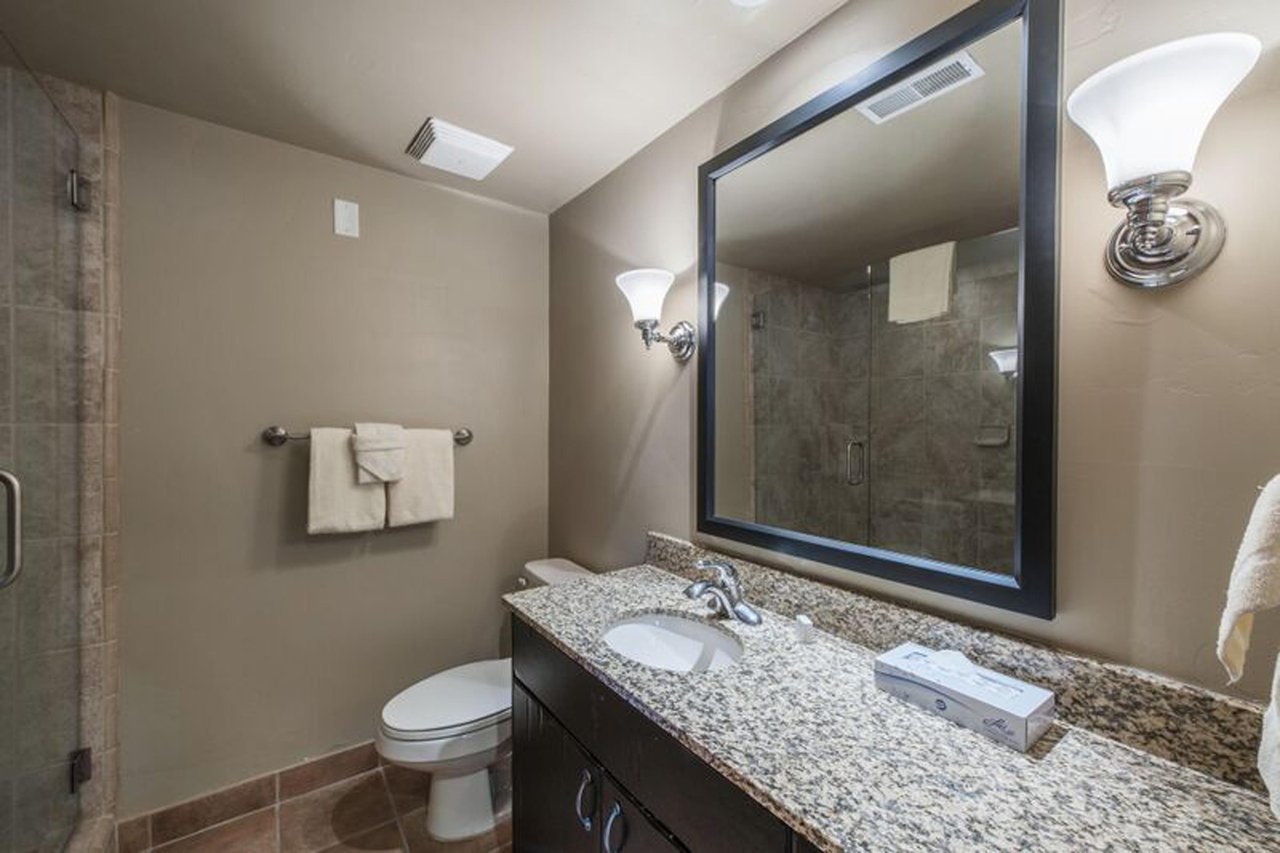 The clean and wellappointed bathroom at Jupiter Inn 10 features granite countertops and a walkin shower, offering everything you need for a comfortable stay at this Park City vacation rental.