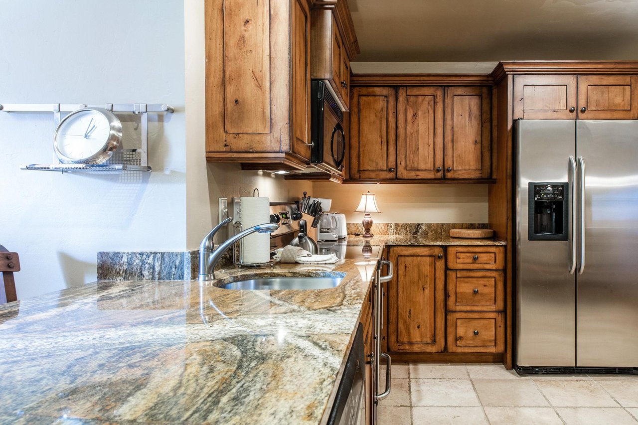 The stunning granite countertops and rich wood cabinetry in the kitchen at Jupiter Inn 17 add a warm and upscale feel to this wellequipped Park City vacation rental studio.